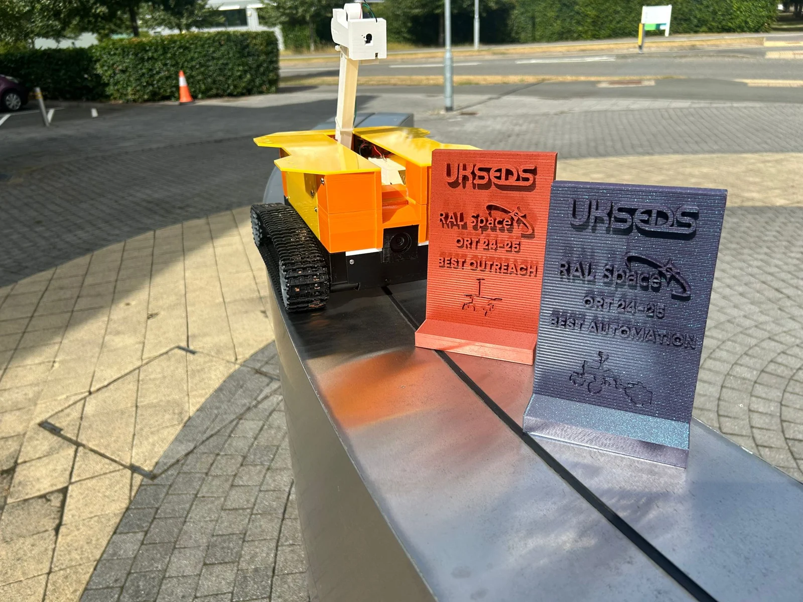 Tracked MarshGazers rover displayed beside competition awards.